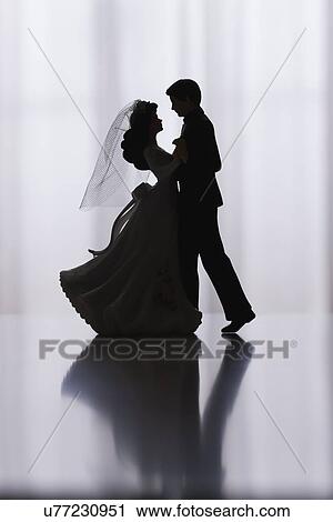 Stock Image - Studio shot of silhouettes of bride and groom figurines dancing. Fotosearch