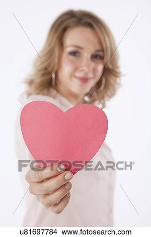 Studio shot of smiling young woman holding pink heart View Large Photo Image Picture - Studio shot of smiling young woman holding pink heart. Fotosearch
