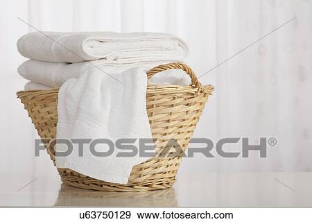 Stock Photo - Studio shot of stack of white towels in Wicker Basket. Fotosearch