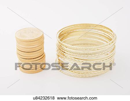 Stock Photo - Studio shot of stacks of golden bracelets and coins. Fotosearch