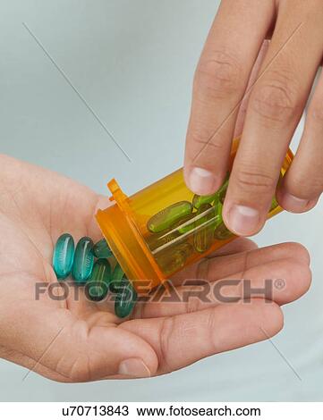 Studio shot of young woman holding capsules View Large Photo Image Stock Image - Studio shot of young woman holding capsules. Fotosearch