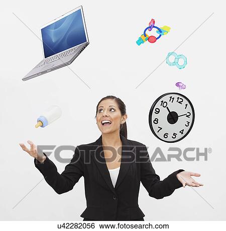 Stock Photograph - Studio shot of young woman juggling with laptop and baby accessories. Fotosearch