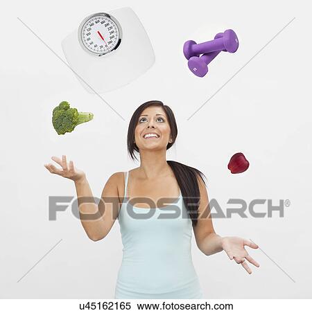 Studio shot of young woman juggling with weight scale, weights, fruit and vegetable View Large Photo Image Stock Photography - Studio shot of young woman juggling with weight scale, weights, fruit and vegetable. Fotosearch