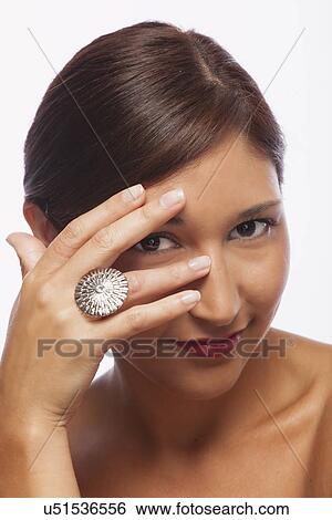Stock Photograph - Studio shot of young woman wearing ring. Fotosearch