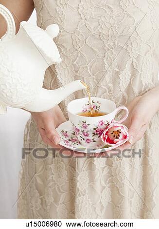 Stock Image - Tea being poured into girl's (2-13) cup. Fotosearch