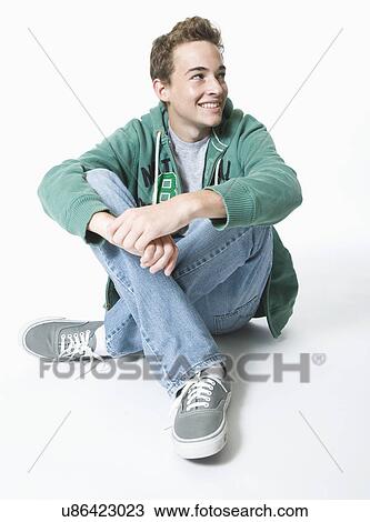 Stock Image - Teenage boy sitting cross-legged. Fotosearch