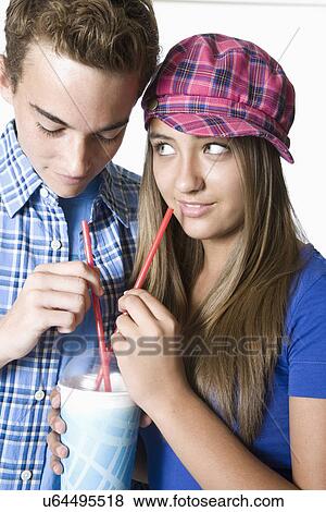 Teenage couple sharing milkshake View Large Photo Image Stock Photo - Teenage couple sharing milkshake. Fotosearch
