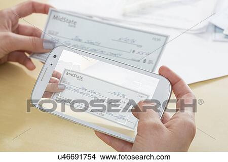 Teenage girl (14-15) photographing cheque with cell phone View Large Photo Image Picture - Teenage girl (14-15) photographing cheque with cell phone. Fotosearch