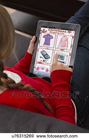 Teenage girl (14-15) sitting and using digital tablet for Christmas shopping View Large Photo Image Stock Photo - Teenage girl (14-15) sitting and using digital tablet for Christmas shopping. Fotosearch