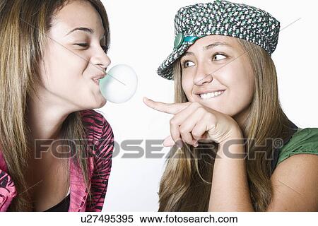 Teenage girl blowing bubble, friend bursting it View Large Photo Image Stock Photography - Teenage girl blowing bubble, friend bursting it. Fotosearch