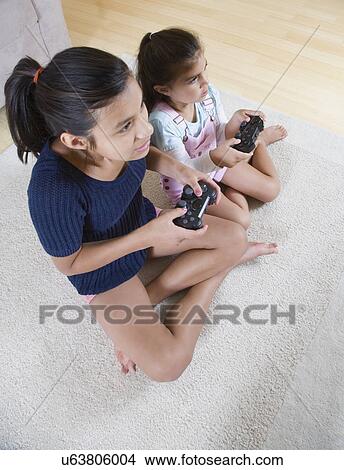 Two girls (6-7, 12-13) playing video game View Large Photo Image Picture - Two girls (6-7, 12-13) playing video game. Fotosearch