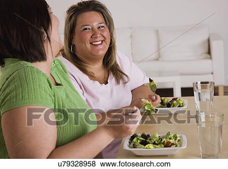 Two women eating salads and laughing View Large Photo Image Stock Photo - Two women eating salads and laughing. Fotosearch