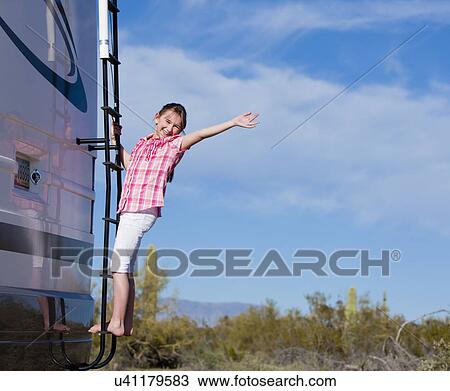 Stock Image - USA, Arizona, Girl (10-11) standing on ladder on motor home. Fotosearch