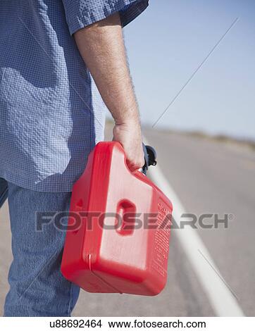 Picture - USA, Arizona, Man standing with canister looking on road. Fotosearch