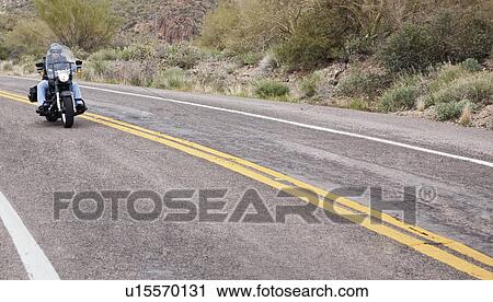 Stock Image - USA, Arizona, Phoenix, Biker on motorcycle in desert area. Fotosearch