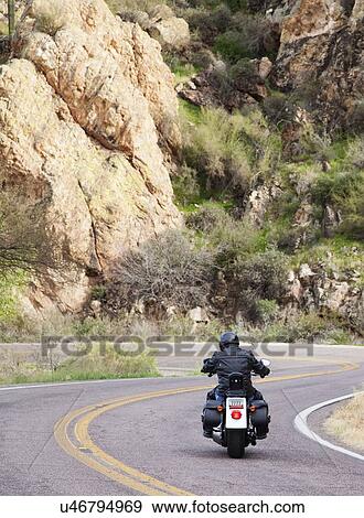 Stock Photo - USA, Arizona, Phoenix, Biker on motorcycle in mountain area. Fotosearch