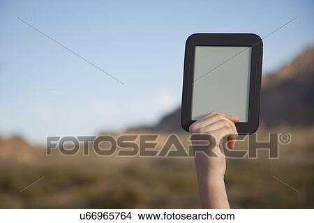 Picture - USA, Arizona, Phoenix, Hand holding digital tablet in mountain area. Fotosearch
