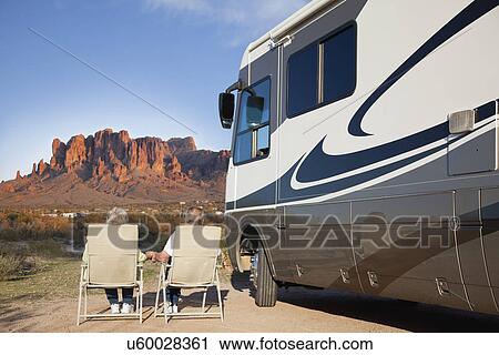 Stock Image - USA, Arizona, Senior couple sitting next to motor home. Fotosearch