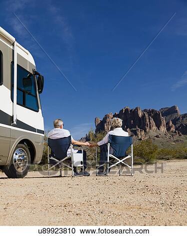 Stock Image - USA, Arizona, Senior couple sitting next to motor home. Fotosearch