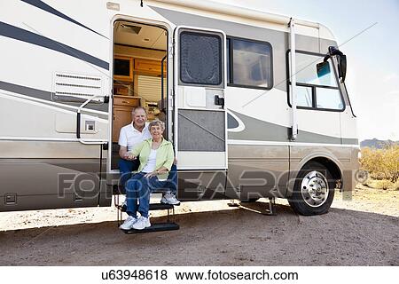 Stock Photo - USA, Arizona, Senior couple sitting next to motor home. Fotosearch