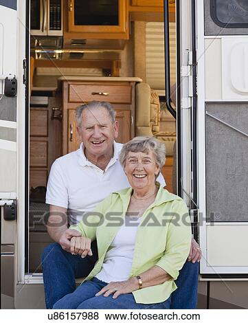 Stock Photo - USA, Arizona, Senior couple sitting next to motor home. Fotosearch