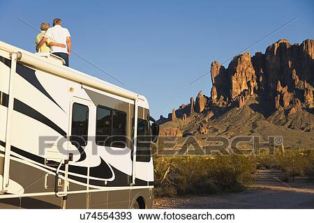 Stock Image - USA, Arizona, Senior couple standing on roof of motor home. Fotosearch