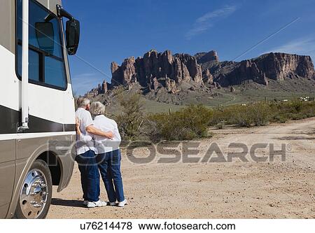 Stock Photo - USA, Arizona, Senior couple standing next to motor home. Fotosearch