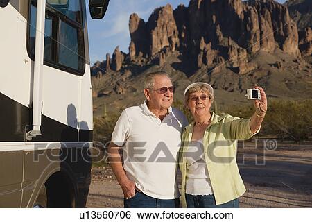 Stock Photograph - USA, Arizona, Senior couple taking photo next to motor home. Fotosearch