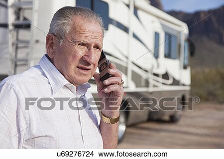 Picture - USA, Arizona, senior man standing in front of mobile home talking on mobile phone. Fotosearch