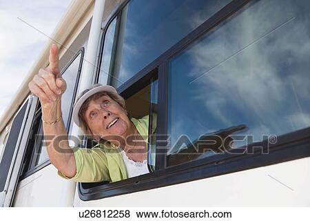 Stock Photo - USA, Arizona, Senior woman wearing sunglasses looking through window of motor home. Fotosearch