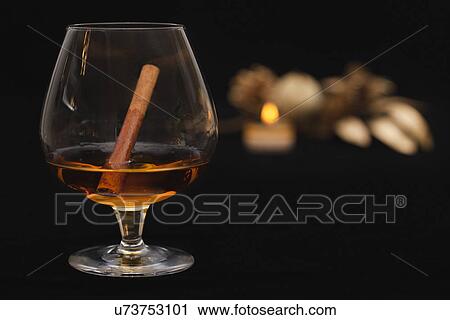 Stock Image - USA California, Fairfax, cinnamon stick in brandy glass. Fotosearch