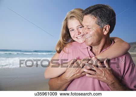 Stock Photo - USA, California, Fairfax, Daughter (10-11) embracing father on beach. Fotosearch