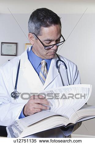Stock Photography - USA, California, Fairfax, doctor reading book in office. Fotosearch