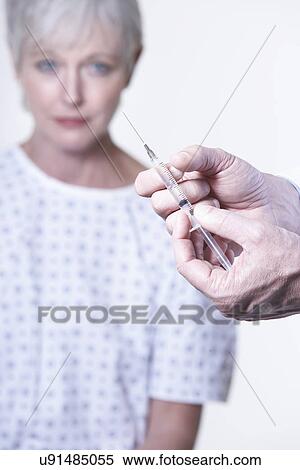 USA, California, Fairfax, Doctor's hands holding syringe, female patient in background View Large Photo Image Stock Photography - USA, California, Fairfax, Doctor's hands holding syringe, female patient in background. Fotosearch