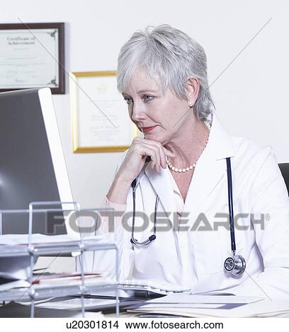 Picture - USA, California, Fairfax, Female doctor sitting in front of computer at desk. Fotosearch