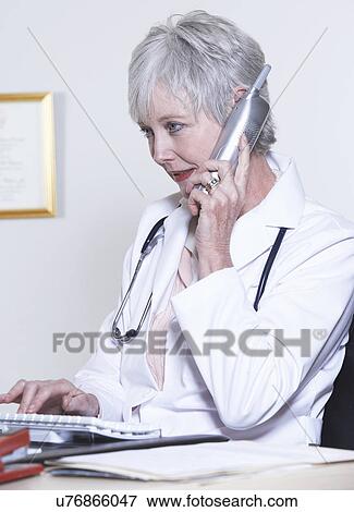 USA, California, Fairfax, Female doctor talking on phone and typing on keyboard View Large Photo Image Stock Photo - USA, California, Fairfax, Female doctor talking on phone and typing on keyboard. Fotosearch