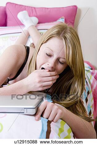 Stock Photo - USA, California, Fairfax, girl (14-15) yawning on bed. Fotosearch