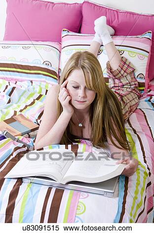 Stock Photography - USA, California, Fairfax, girl (14-15) reading on bed. Fotosearch