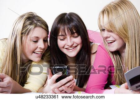 Stock Image - USA, California, Fairfax, girls (15-18) text messaging on bed. Fotosearch