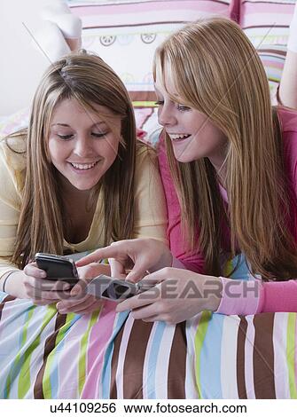 Stock Photograph - USA, California, Fairfax, girls (15-18) text messaging on bed. Fotosearch