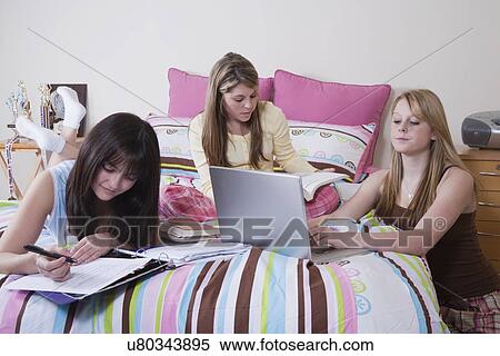 Stock Photography - USA, California, Fairfax, girls (15-18) doing homework on bed. Fotosearch