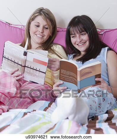 Stock Image - USA, California, Fairfax, girls (17-18) reading on bed. Fotosearch