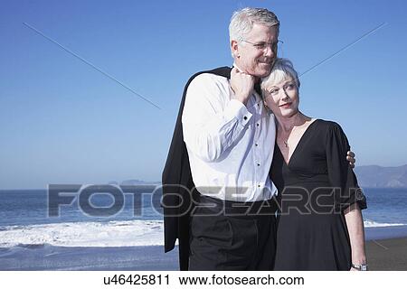 Stock Image - USA, California, Fairfax, Happy mature couple hugging on beach. Fotosearch