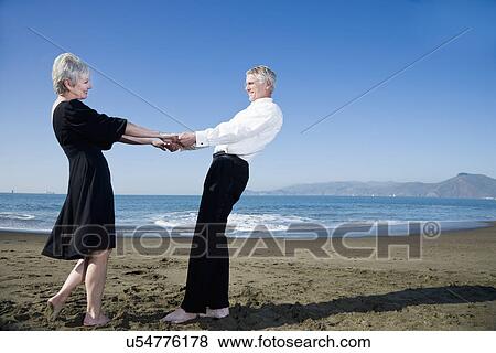 Stock Photo - USA, California, Fairfax, Happy mature couple dancing on beach. Fotosearch