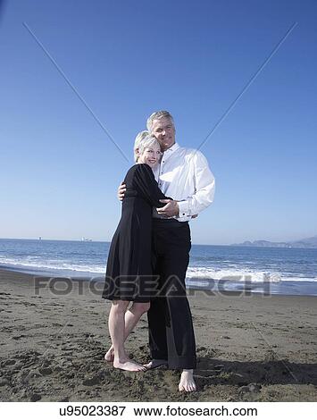 Stock Photo - USA, California, Fairfax, Happy mature couple hugging on beach. Fotosearch