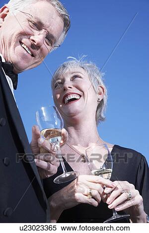 Stock Photography - USA, California, Fairfax, Happy mature couple drinking wine on beach. Fotosearch