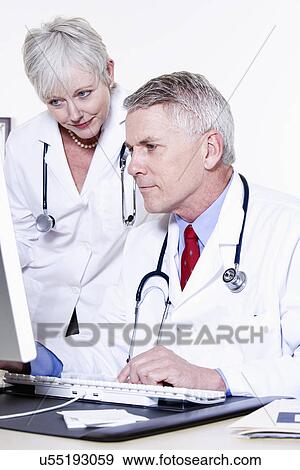Stock Photo - USA, California, Fairfax, Male and female doctor looking at computer together. Fotosearch