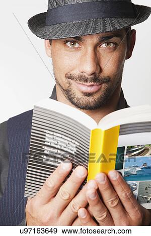 Stock Photo - USA, California, Fairfax, Man wearing hat reading book. Fotosearch