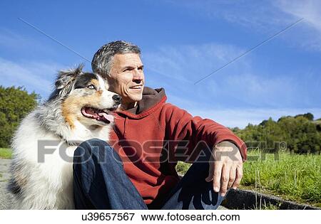 Stock Photo - USA, California, Fairfax, Mature man with dog looking away. Fotosearch