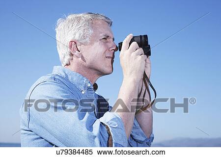 USA, California, Fairfax, Mature man looking through binoculars against blue sky View Large Photo Image Stock Photography - USA, California, Fairfax, Mature man looking through binoculars against blue sky. Fotosearch